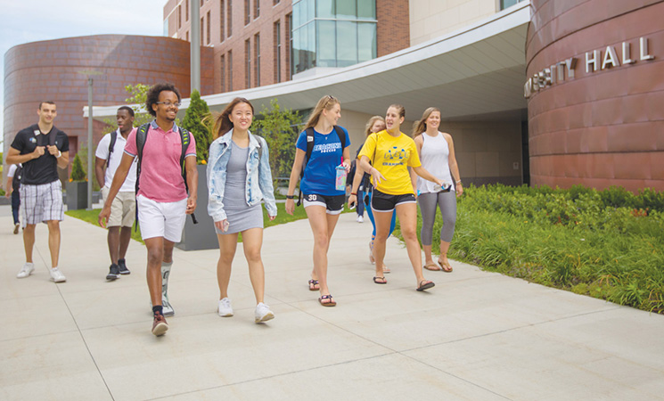 Eight students walking past University Hall in summer